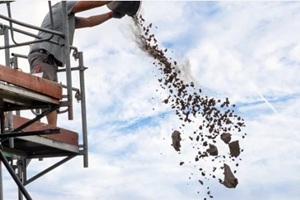 construction worker disposes rubble from a bucket on a tall scaffold during a renovation project