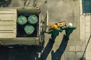workers in green uniforms unload containers from a Virginia Beach bulk trash pickup home