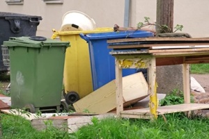 old discarded household furniture dumped by colorful plastic dumpsters for bulk Item pickup