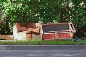 old sofa and household furniture dumped on the street prepared for bulk item curbside pickup collection by city cleaning services