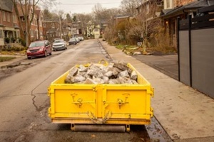 construction dumpster filled with broken concrete placed on a residential street in Toronto’s Beaches neighbourhood during winter