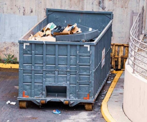 large industrial dumpster filled with various types of trash and debris outdoors