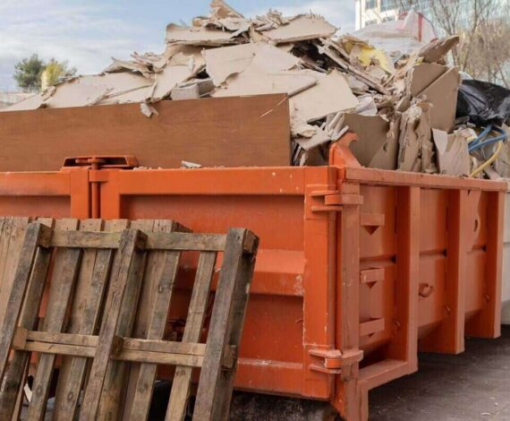 huge heap on metal big overloaded dumpster waste container filled with construction waste