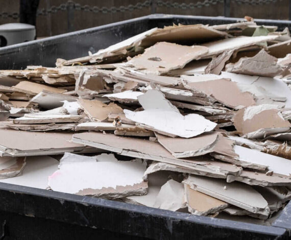 an overloaded dumpster waste container, with construction waste and drywall plasterboard, debris generated during the reconstruction process