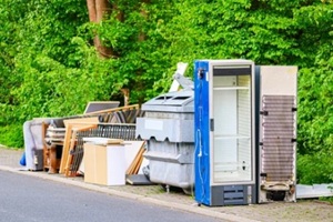 discarded household appliances and furniture piled up for collection on the roadside