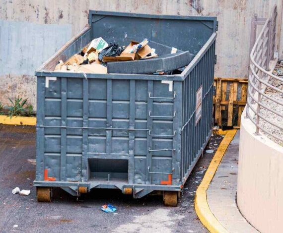 large industrial dumpster filled with various types of trash and debris outdoors