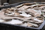 an overloaded dumpster waste container, with construction waste and drywall plasterboard, debris generated during the reconstruction process