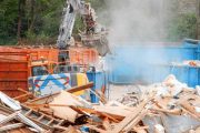 construction site with heavy machinery working on debris removal in a city area during daytime hours