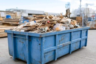 industrial dumpster with construction waste under bright sky, minimalist composition