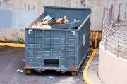 large industrial dumpster filled with various types of trash and debris outdoors