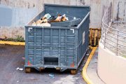 large industrial dumpster filled with various types of trash and debris outdoors